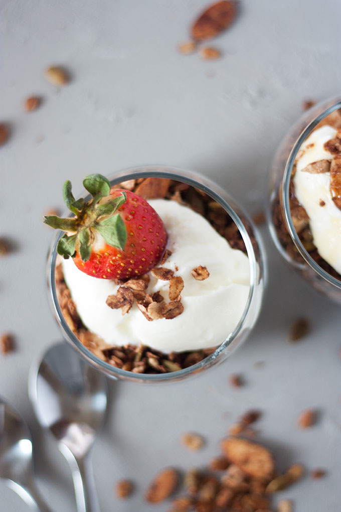 overhead of chocolate granola with yogurt and a strawberry