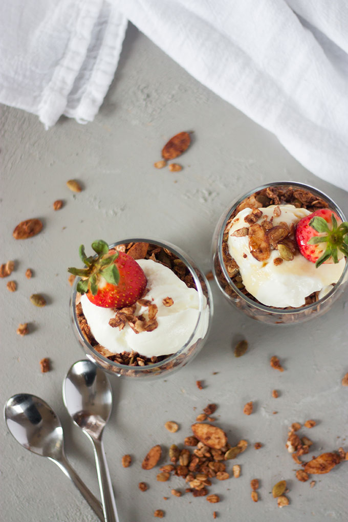 overhead of two chocolate granola pots with yogurt and berries