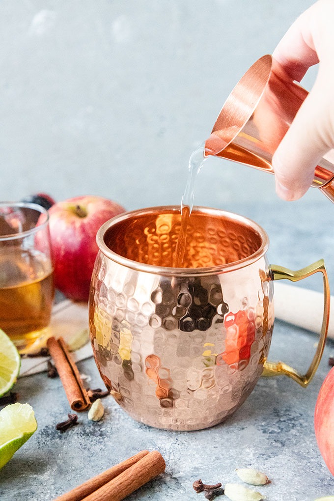 vodka being poured into a copper mug