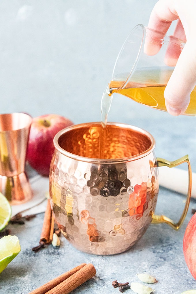 spiced simple syrup being poured into copper mug