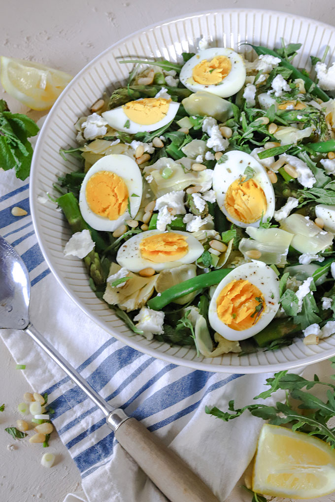 artichoke salad on blue napkin with rustic spoon and lemon wedge