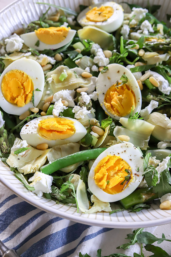 close up of egg in artichoke salad on a blue napkin