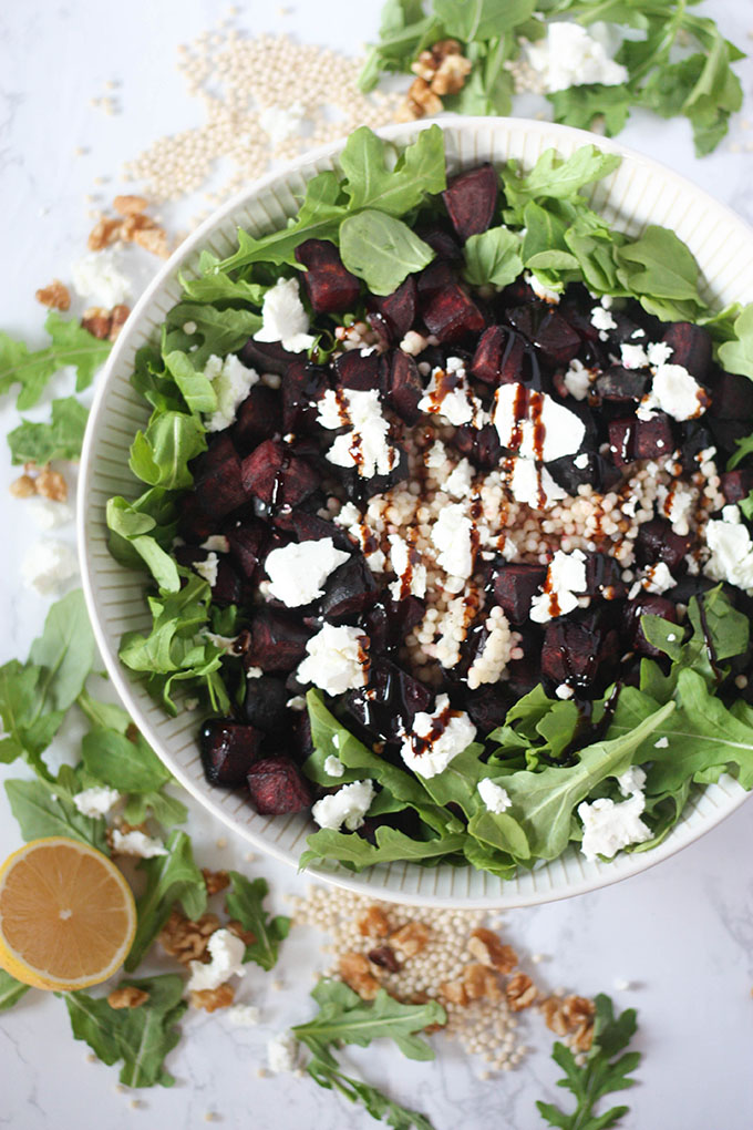 beetroot goat cheese salad in white bowl surrounded by ingredients