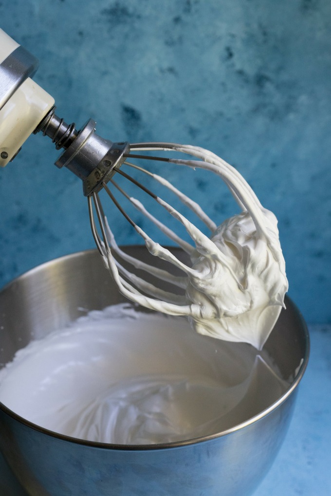 thick and glossy meringue mixture on a whisk attached to a kitchen aid