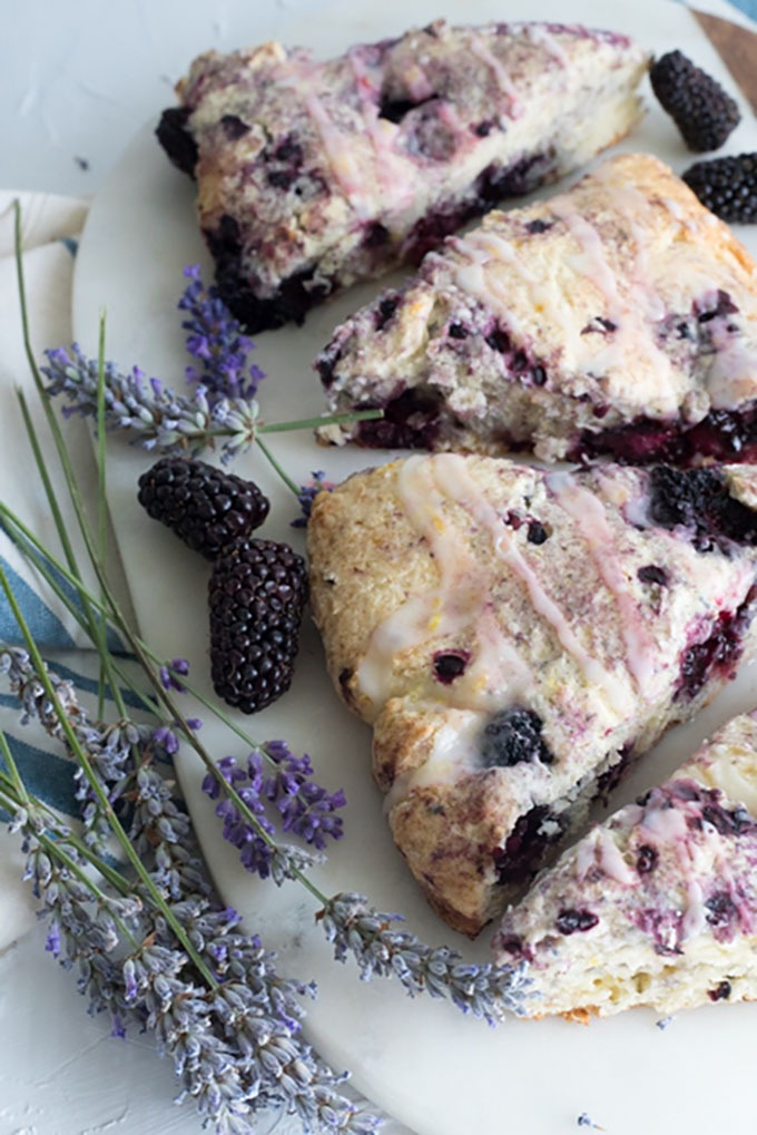 close up of blackberry scones on a marble board with fresh lavender and blackberries