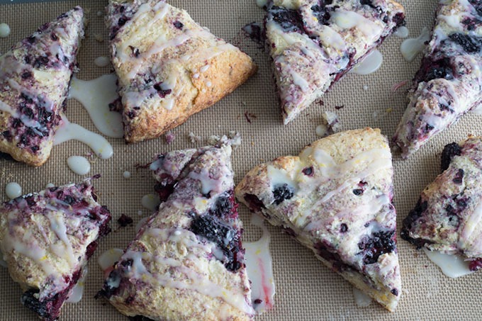 blackberry scones on silicone baking mat, drizzled with lemon glaze