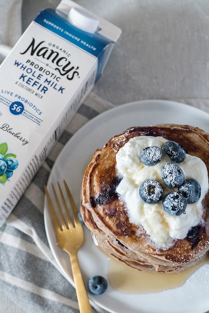 overhead of kefir pancakes, carton of nancys blueberry kefir to left of pancake stack