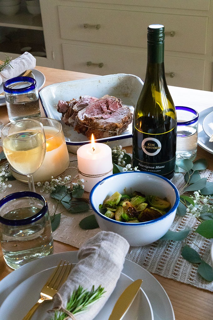 lamb and side dishes on table with wine