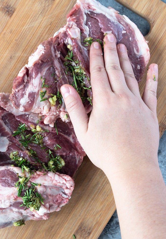 hand marinating lamb on board