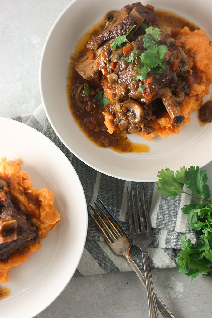 two plates of bourbon ribs on a grey linen