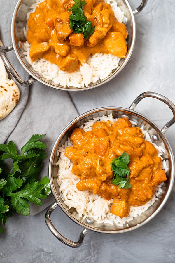 two dishes of chicken massaman curry on grey board