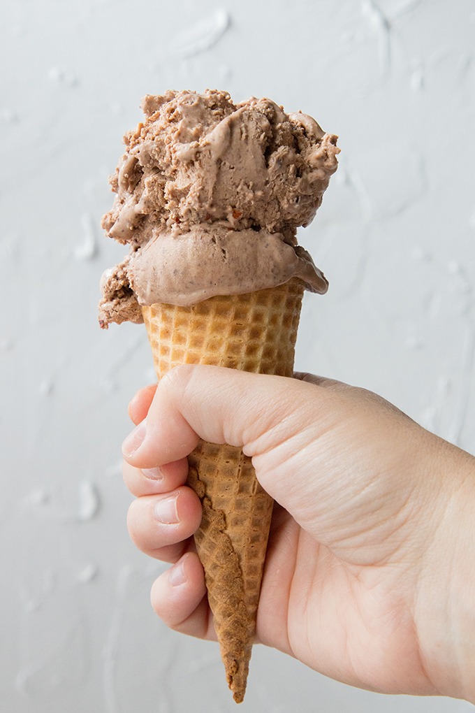 hand holding chili chocolate ice cream cone in front of white board