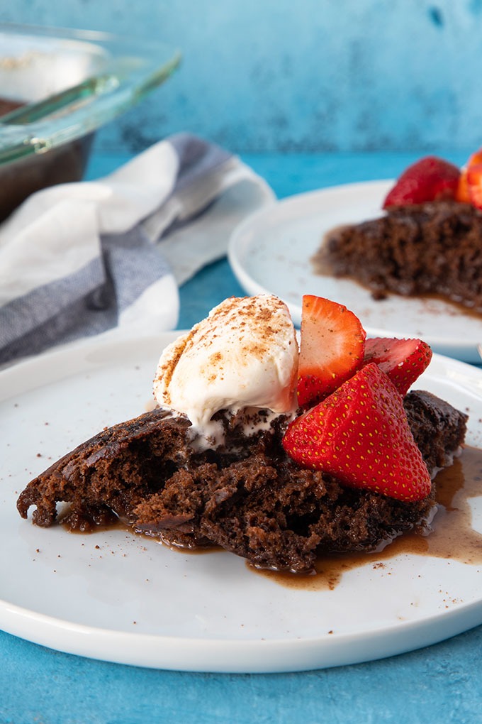 chocolate self saucing pudding on white plate with ice cream and strawberries