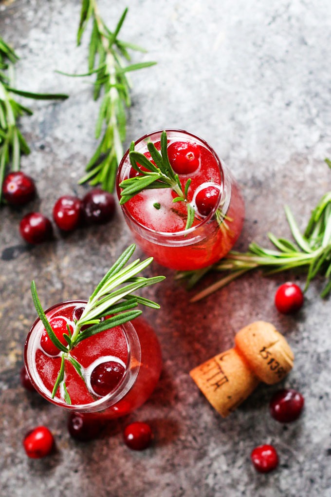 two cranberry peach Bellinis on grey board with rosemary and fresh cranberry