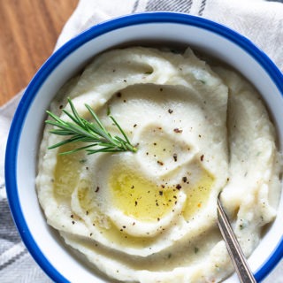 creamy mashed cauliflower in white bowl on wooden board