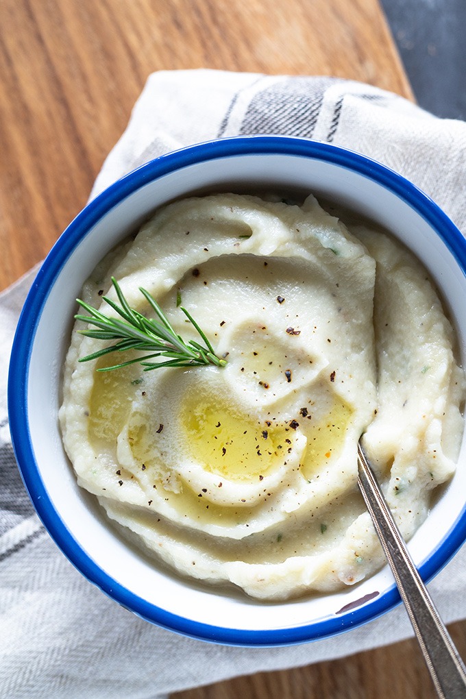 creamy mashed cauliflower in white bowl on wooden board