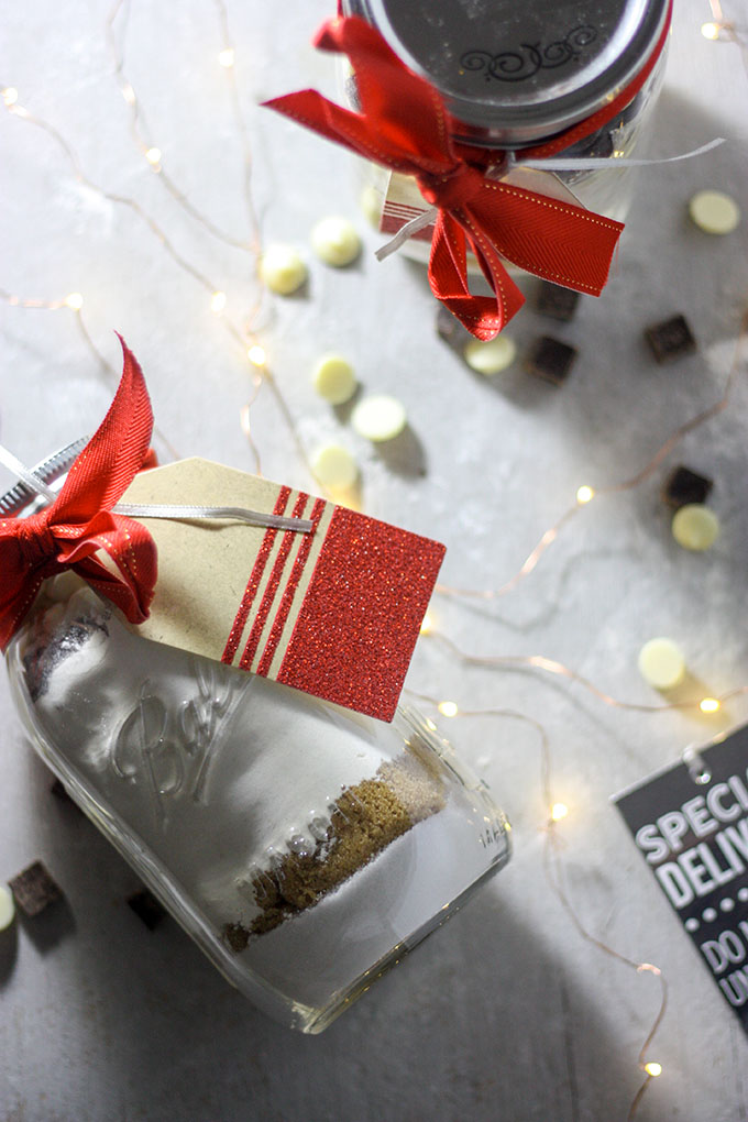 chocolate chip jar cookies mixture in jar surrounded by white chocolate and christmas lights and cards