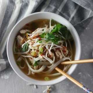 bowl of chicken pho on grey napkin with chopsticks in bowl