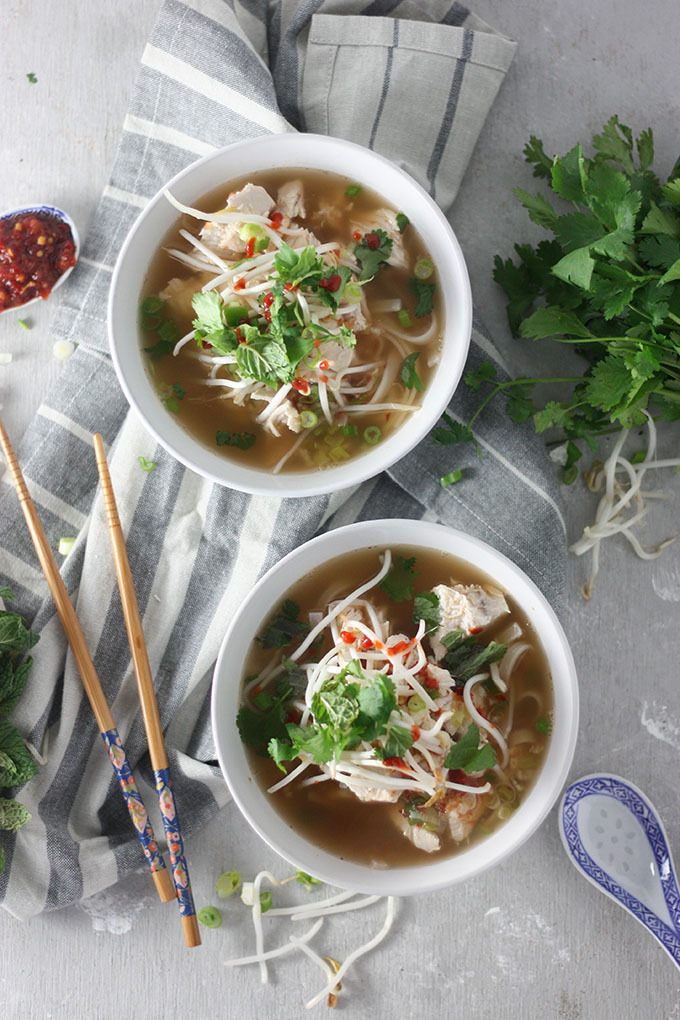 two bowls of pho on grey napkin, chopsticks to left fresh mint to right of bowl