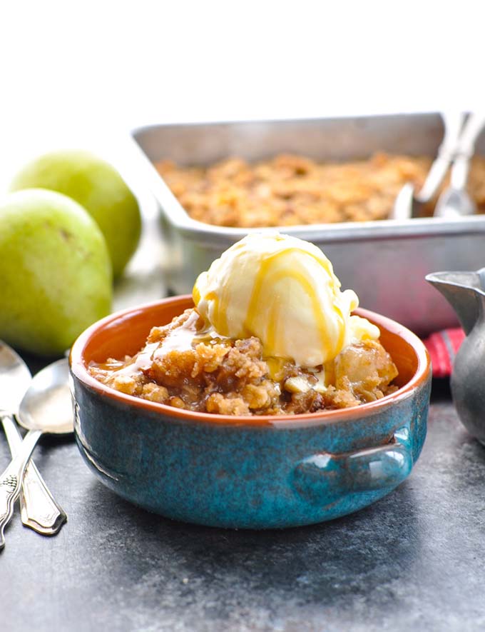 pear crisp in blue bowl with pears in background