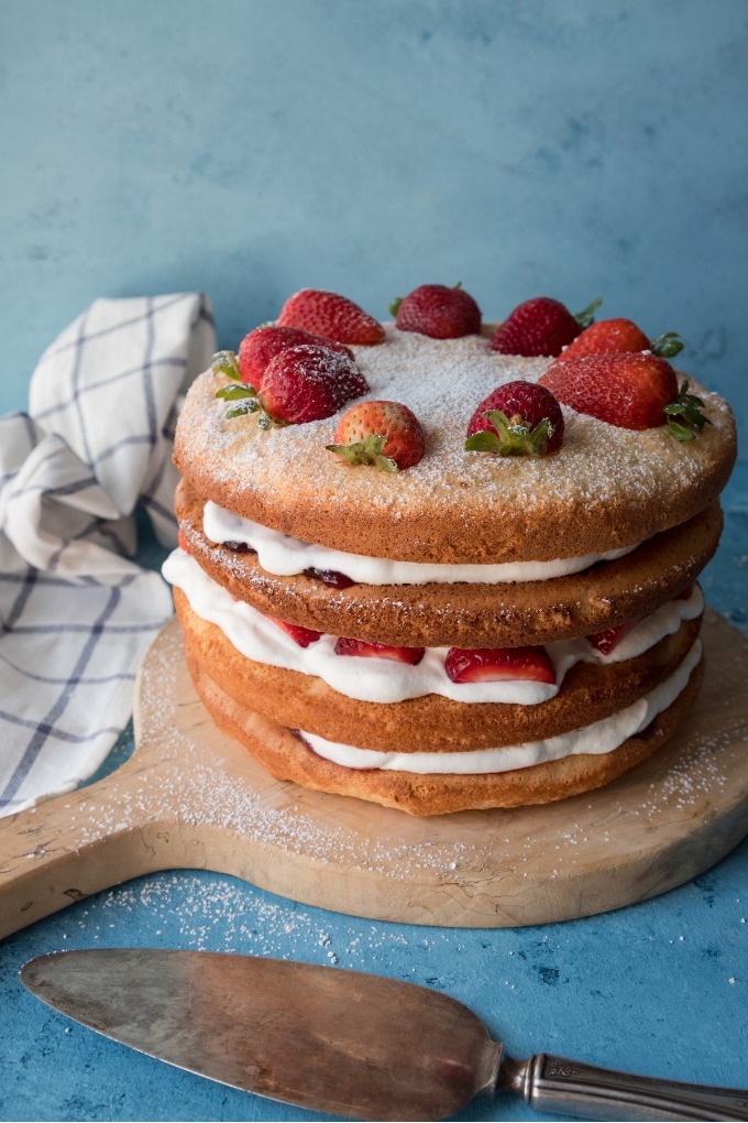 fluffy sponge cake on antique wooden board with antique serving knife