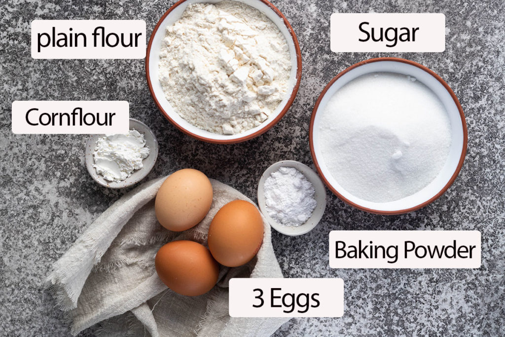 sponge cake ingredients on board; eggs, cornflour, plain flour, sugar, baking powder