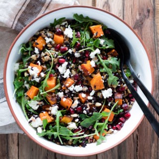 grain salad in white bowl on wooden board