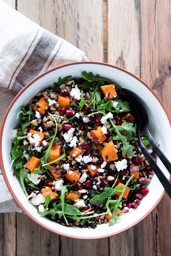 grain salad in white and brown bowl on wood surface