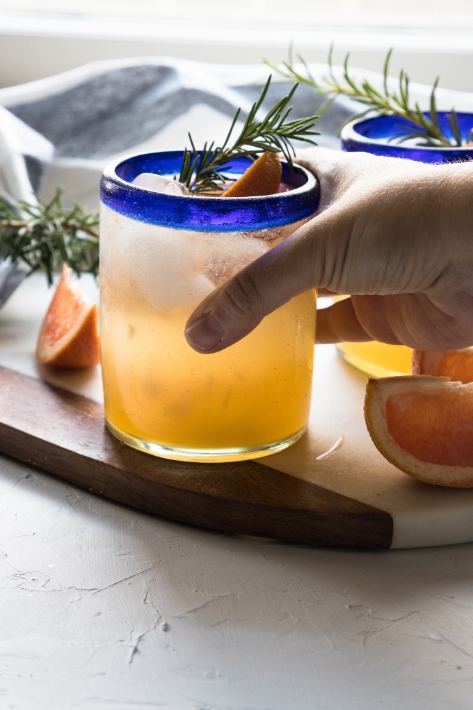 hand reaching out to grab a grapefruit gin cocktail