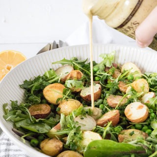 honey mustard dressing being poured over roasted potato salad