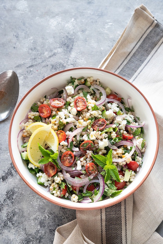 overhead israeli couscous in white bowl with antique spoon