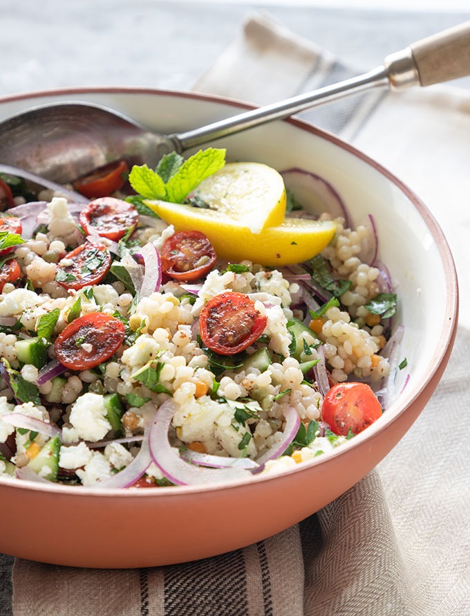 israeli couscous salad in white terra-cotta bowl