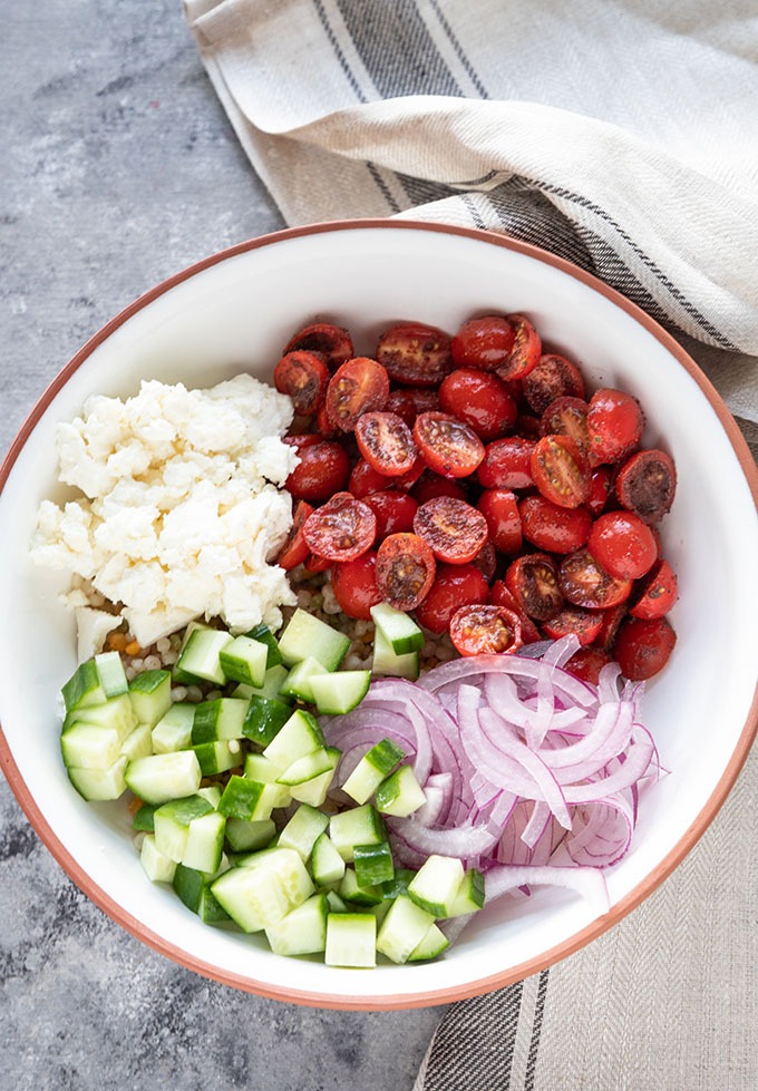 salad ingredients unmixed in a white and terra-cotta bowl