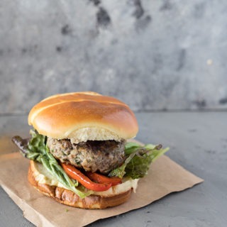 single lamb burger with feta on brown parchment paper