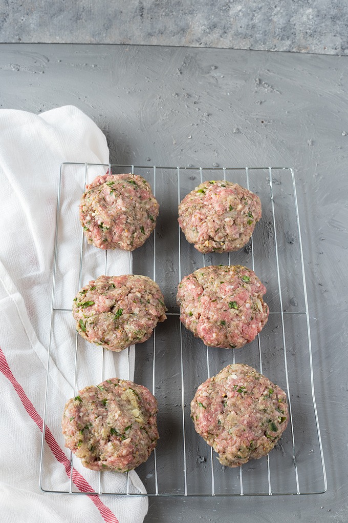 six raw lamb burger patties on a wire rack