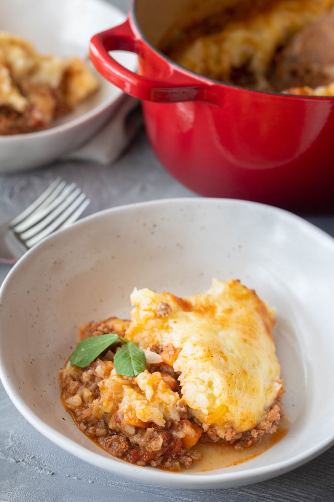 lamb shepherd's pie in white bowl in front of dutch oven