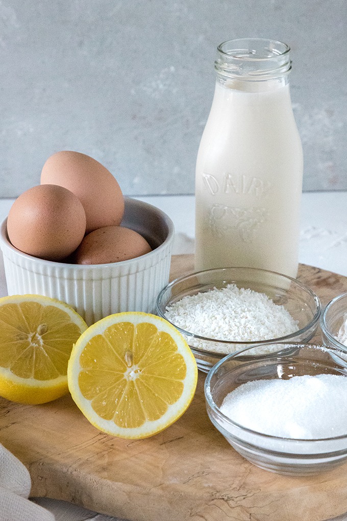 lemon coconut tart ingredients on wood board - eggs, lemons, flour, cream, sugar and coconut