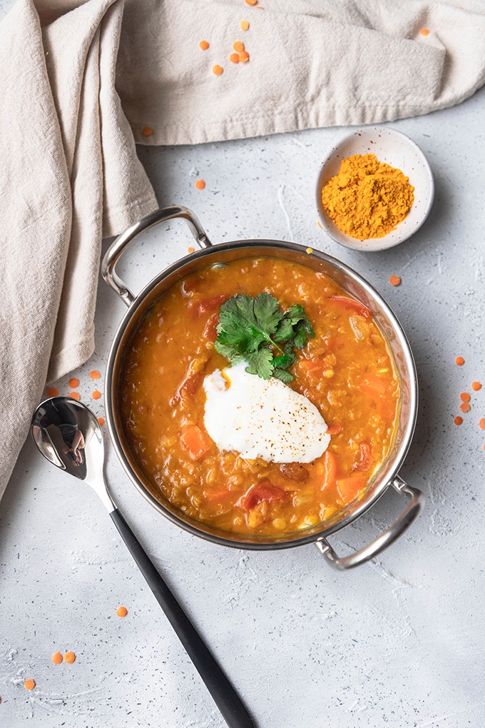 lentil dal in metal dish with spoon and turmeric