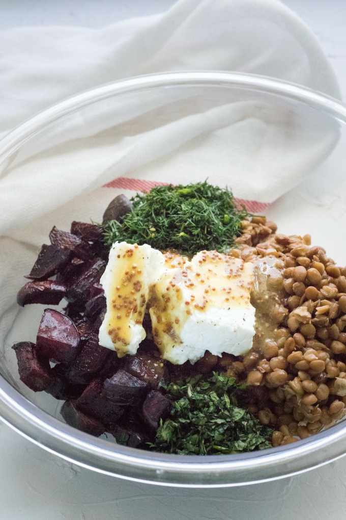 feta lentil salad ingredients in a clear bowl with dressing