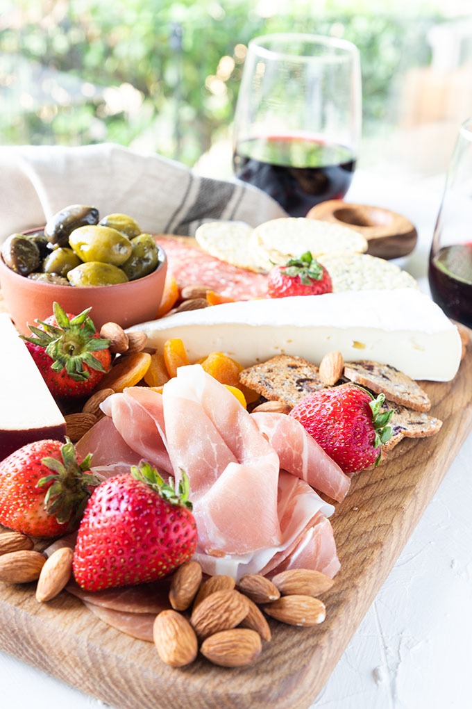 meat and cheese board featured in front of window with two glasses of red wine