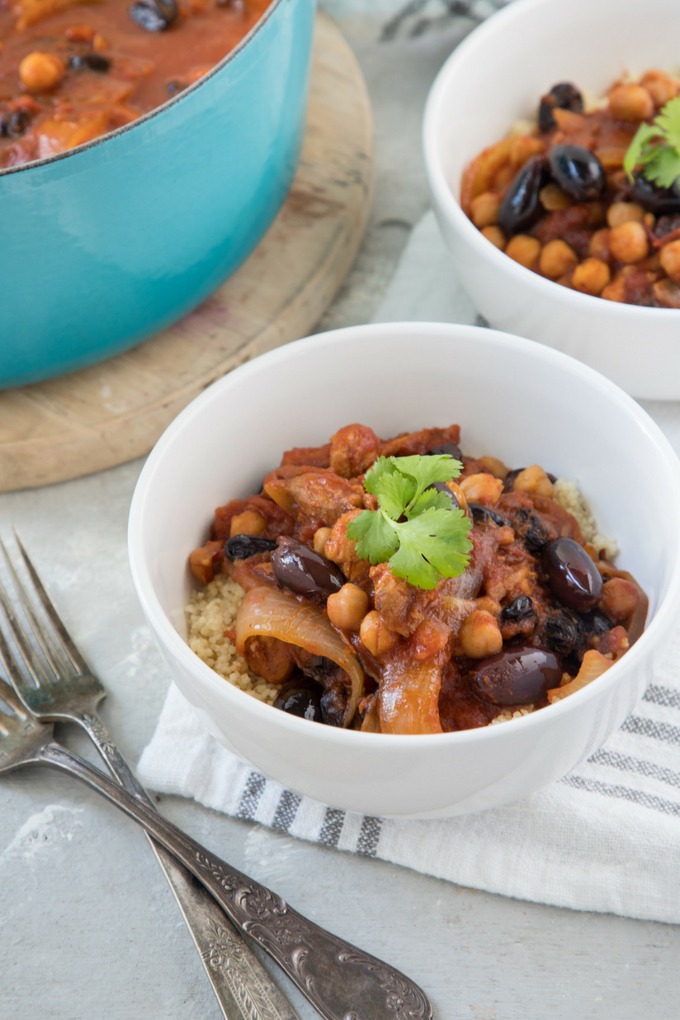 a bowl of moroccan chicken stew and a blue dutch oven on round board