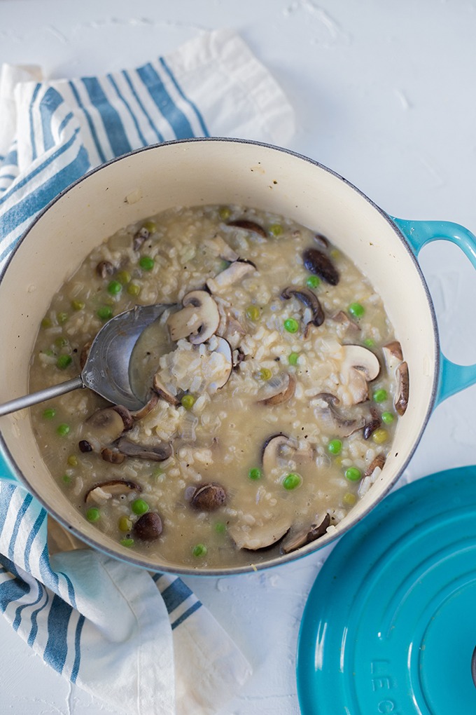 mushroom and pea risotto in a blue dutch oven on a blue and white linen