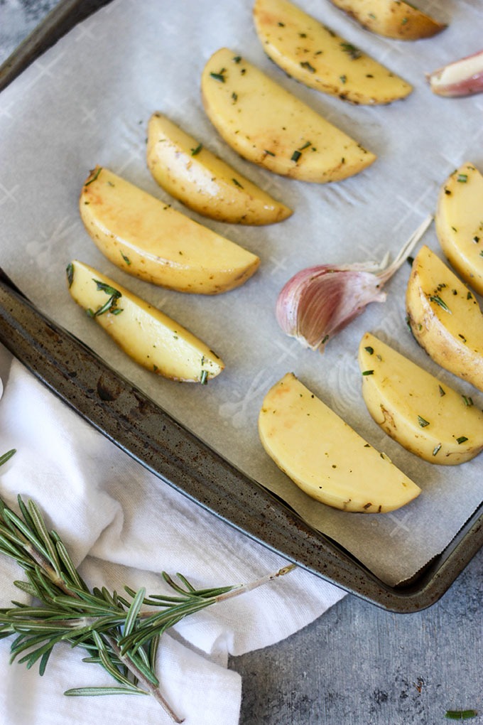 raw potatoes on a baking tray lined with baking paper