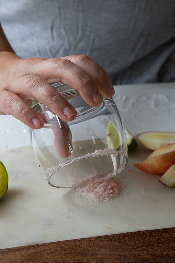 person holding glass in pile of salt to rim the glass