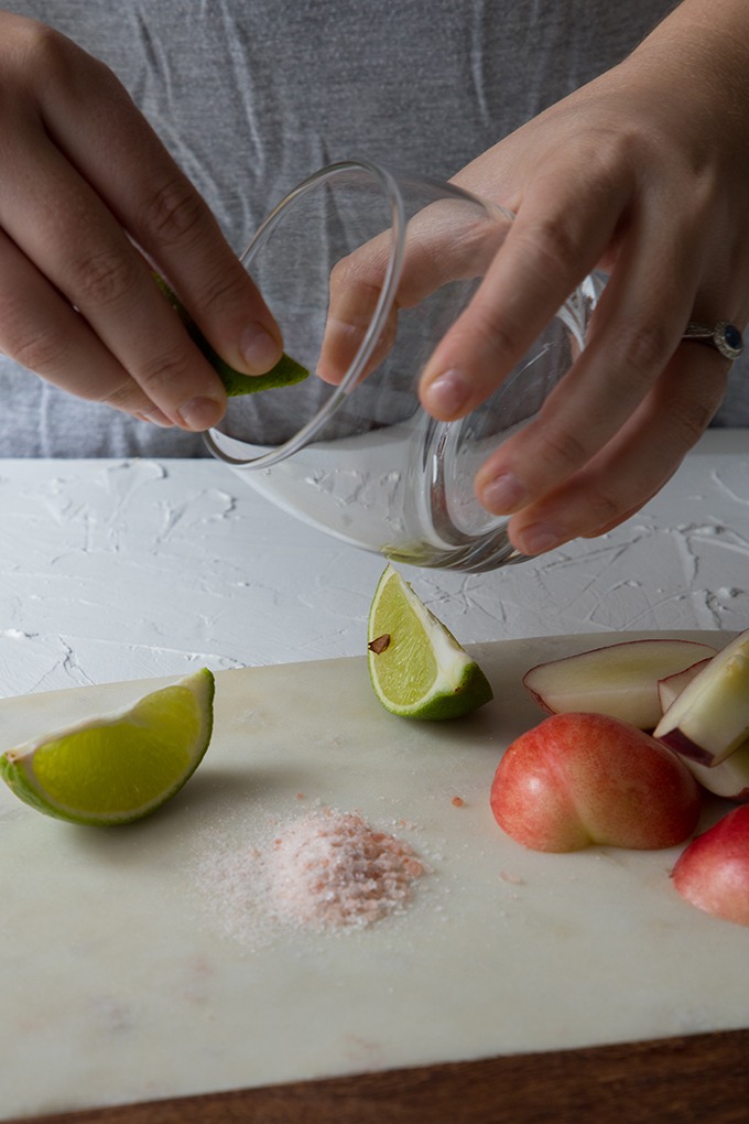 person holding glass, rubbing lime juice around the glass rim to salt