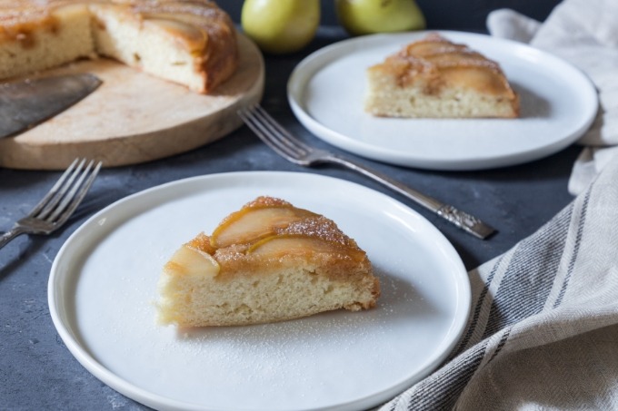 two slices of pear upside-down cake on white plates