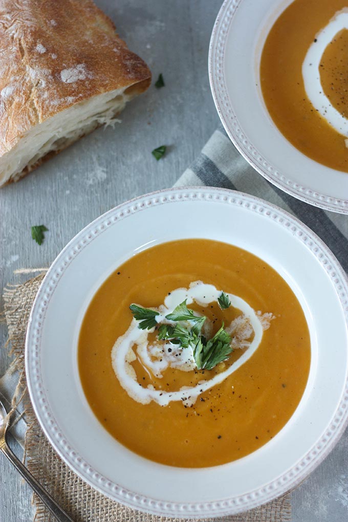 overhead of two bowls of pumpkin sweet potato soup on hessian square and grey napkin