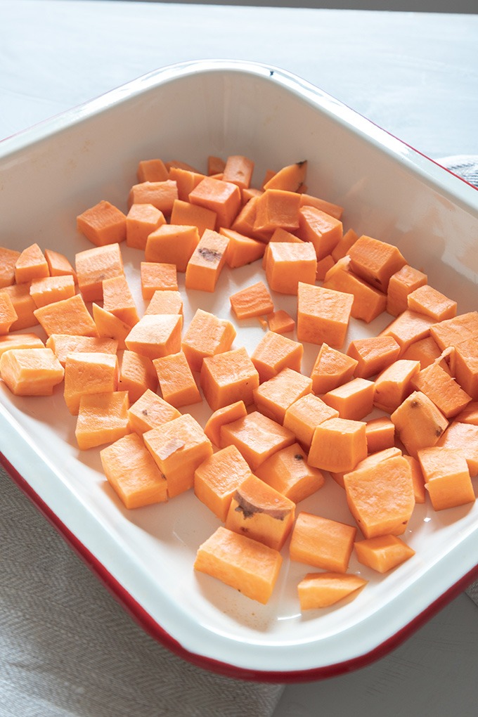 raw sweet potato in red and white enamel dish