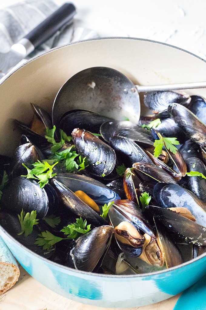 blue dutch oven filled with rosé wine mussels with antique spoon