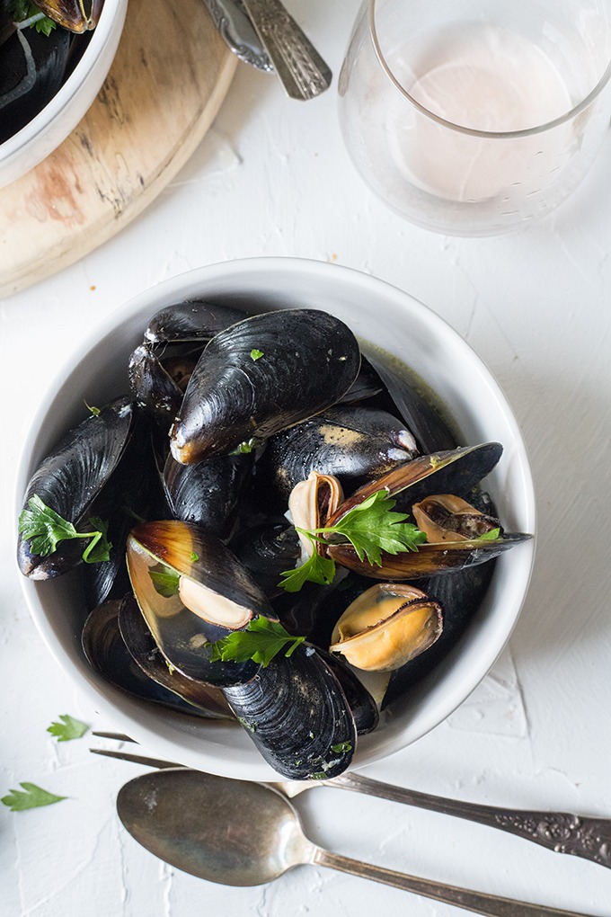 bowl of wine mussels on white board next to antique board